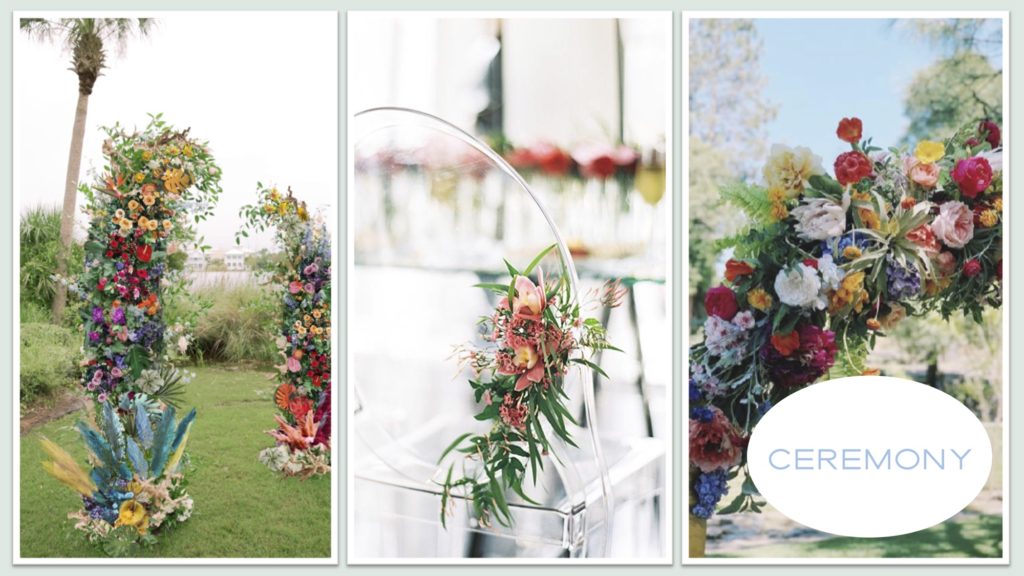 A colorful wedding arbor sits on lush green grass. A lucite chair is decorate with red flowers and greenery.